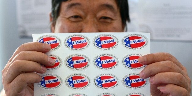 Election official Henry Tung displays a sheet of 'I Voted' stickers in various languages at a polling station at St. Paul's Lutheran Church in Monterey Park, Los Angeles County, on November 6, 2012 in California, as Americans flock to the polls nationwide to decide between President Barack Obama, his Rebuplican challenger Mitt Romney, and a wide range of other issues. Monterey Park is one of six cities in California's 49th Assembly District, the state's first legislative district where Asian-Americans make up the majority of the population. AFP PHOTO/Frederic J. BROWN (Photo credit should read FREDERIC J. BROWN/AFP/Getty Images)