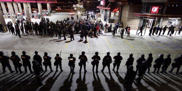 Police officers in riot gear hold a line as they watch demonstrators protest the shooting death of Michael Brown and 18-year-old Vonderrit Myers Jr. at a QuikTrip convince store and gas station October, 12 2014 in St. Louis, Missouri. Civil rights organizations, protest groups and people from around the country were protesting the August 9 shooting of Brown, which involved Ferguson Police officer Darren Wilson and Meyers, who was shot and killed last week by an off duty St. Louis police officer. AFP PHOTO/Joshua Lott (Photo credit should read Joshua LOTT/AFP/Getty Images)