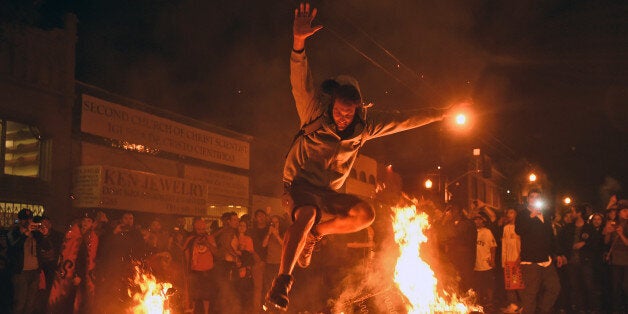 A man jumps over some debris that has been set on fire in the Mission district after the San Francisco Giants beat the Kansas