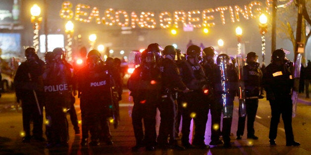 Police gather on the street as protesters react after the announcement of the grand jury decision Monday, Nov. 24, 2014, in Ferguson, Mo. A grand jury has decided not to indict Ferguson police officer Darren Wilson in the death of Michael Brown, the unarmed, black 18-year-old whose fatal shooting sparked sometimes violent protests. (AP Photo/Charlie Riedel)