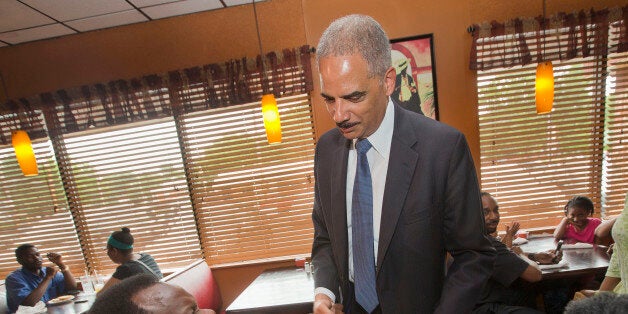 Attorney General Eric Holder stops to shake hands with a patron at Drake's Place Restaurant, before his meeting with local community leaders, Wednesday, Aug. 20, 2014 in Ferguson, Mo. Holder arrived in Missouri on Wednesday, a small group of protesters gathered outside the building where a grand jury could begin hearing evidence to determine whether a Ferguson police officer who shot 18-year-old Michael Brown should be charged in his death. (AP Photo/Pablo Martinez Monsivais, Pool)