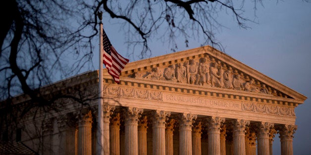 The U.S. flag flies in front of the Supreme Court building at sunset in Washington, D.C., U.S., on Tuesday, Dec. 9, 2014. Workers don't have a federal right to be paid for time spent in post-shift security searches, the U.S. Supreme Court ruled in a decision that will help Amazon Inc. fend off lawsuits seeking more than $100 million. Photographer: Andrew Harrer/Bloomberg via Getty Images