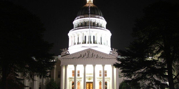 A Capitol building in the Classical Style, with a domed rotunda, Greek columns, and a flag flying in the night breeze.