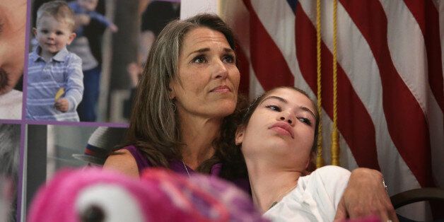WASHINGTON, DC - APRIL 22: Liza Smith (L) of White Stone, Virginia, comforts her14-year-old Haley Smith (R) who suffers from a severe form of epilepsy called Dravet Syndrome, as she listens during a news conference at the National Press Club April 22, 2015 in Washington, DC. U.S. Rep. Scott Perry (R-PA) discussed during the news conference his proposed Charlotte's Web Medical Access Act to legalize therapeutic hemp and cannabidiol (CBD) by excluding them from the Controlled Substance Act. (Photo by Alex Wong/Getty Images)