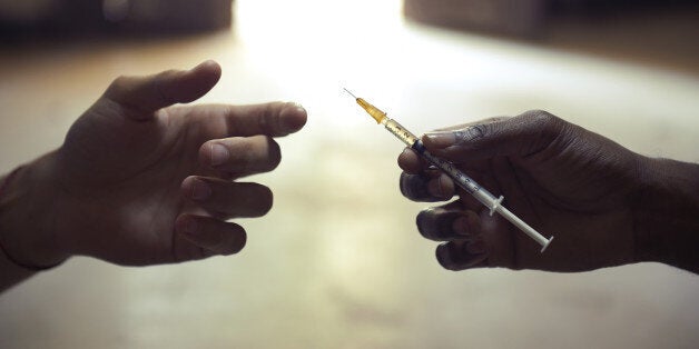 People abusing drugs, with African american man and caucasian guy sharing the same syringe to inject heroin