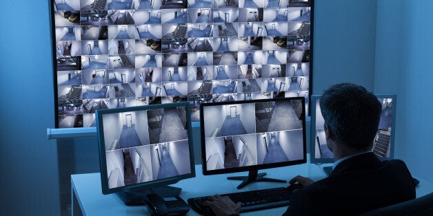 Rear View Of A Man In Control Room Monitoring Multiple Cctv Footage