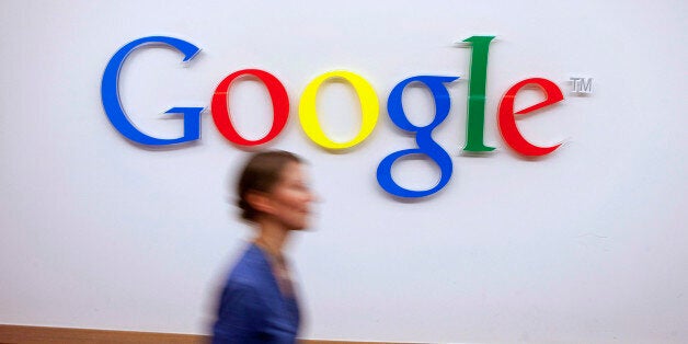 A Google Inc. employee walks past a logo outside the entrance to the company's offices in Berlin, Germany, on Friday, Aug. 16, 2013. Google, based in Mountain View, California, is seeking to revive Motorola Mobility's smartphone business, recently announcing a new flagship Moto X smartphone with customizable colors that will be assembled in the U.S. Photographer: Krisztian Bocsi/Bloomberg via Getty Images