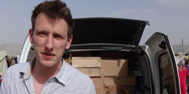 This undated photo provided by Kassig Family shows Peter Kassig standing in front of a truck filled with supplies for Syrian refugees. Confronted by terrorists beheading Americans, President Barack Obama has ordered a review of how the United States responds when citizens are taken hostage overseas. (AP Photo/Courtesy Kassig Family)