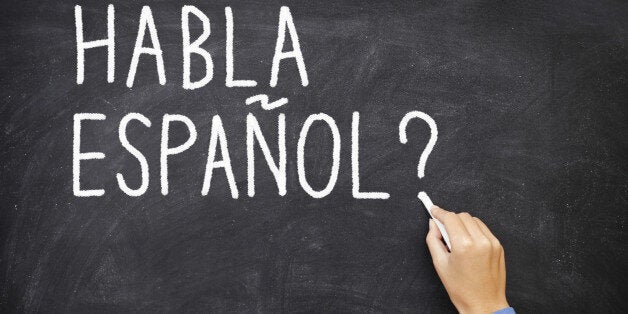 Spanish language learning concept image. Teacher or student writing 'habla espanol' on blackboard during spanish language course class. More: