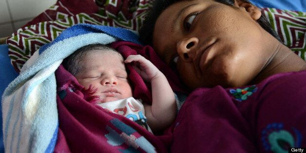 Indian mother Sonia (R) looks on as her newborn baby girl sleeps at a government hospital in Amritsar on July 11, 2013, on the occasion of World Population Day. Africa and Asia are the continents that will see the fastest urban population growth in the next 40 years, a UN report said earlier in the year noting that India and China are leading the surge. The Earth's population is expected to roughly triple by 2050 compared to a century earlier. It stood at three billion in 1950, reached seven billion in 2011 and is likely to reach about 9.5 billion by 2050 -- a rise that will occur especially in the poorest countries, according to UN estimates. AFP PHOTO/NARINDER NANU (Photo credit should read NARINDER NANU/AFP/Getty Images)