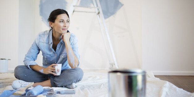Woman relaxing with coffee among painting supplies