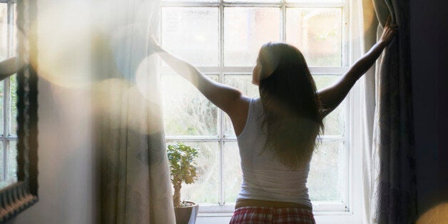 woman opening curtains in the morning