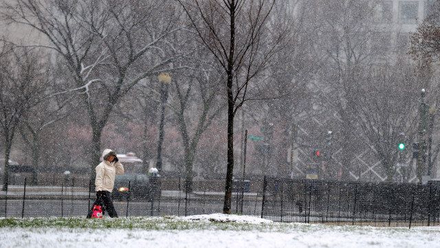 A woman walks during a snowfall on March 25, 2013 in Washington, DC. A messy Monday is in store for millions along the East Coast, with winter weather advisories warning of a mixture of snow and rain for Washington, DC, Philadelphia, metropolitan New York and parts of northeast New Jersey. AFP PHOTO/Jewel Samad (Photo credit should read JEWEL SAMAD/AFP/Getty Images)
