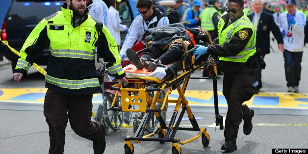 BOSTON - APRIL 15: A person who was injured in the first explosion is wheeled across the finish line of the Boston Marathon. (Photo by John Tlumacki/The Boston Globe via Getty Images)