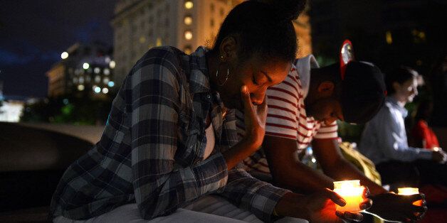 WASHINGTON, DC - SEPTEMBER 16: Brittany Carter, center, and Jibri Johnson, right center, take part in a candle light vigil at Freedom Plaza for the mass shooting at the U.S. Navy Yard on Monday September 16, 2013 in Washington, DC. (Photo by Matt McClain/ The Washington Post via Getty Images)