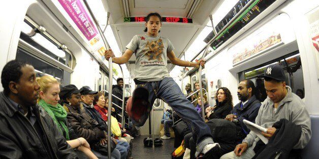 New York City Subway dancer Marcus Walden aka Mr Wiggles performs acrobatic tricks on the subway while passengers watch November 23, 2010. The dance crew of Donte Steele (Thebestuknow); Tamiek Steele ( B/Boy LJ) and Marcus Walden ( Mr Wiggles) perform their roughly 45-second routine between stops on the train running from 125th Street in Harlem to the Brooklyn Bridge. AFP PHOTO / TIMOTHY A. CLARY (Photo credit should read TIMOTHY A. CLARY/AFP/Getty Images)