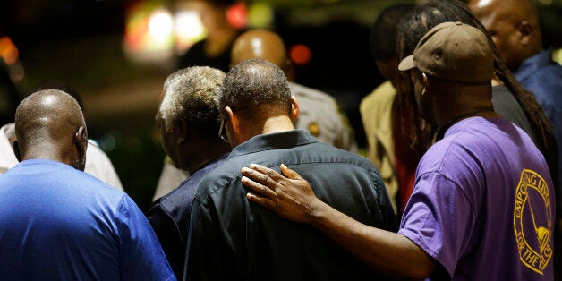 Worshippers gather to pray in a hotel parking lot across the street from the Emanuel AME Church following a shooting Wednesday, June 17, 2015, in Charleston, S.C. (AP Photo/David Goldman)