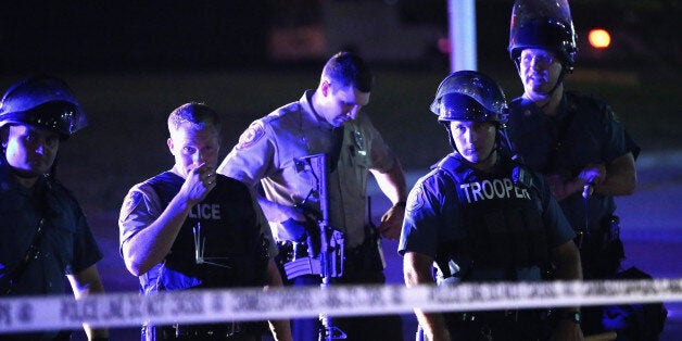 FERGUSON, MO - AUGUST 11: Police lock down a neighborhood, refusing to let people leave on August 11, 2014 in Ferguson, Missouri. Police responded with tear gas as residents and their supporters protested the shooting by police of an unarmed black teenager named Michael Brown who was killed Saturday in this suburban St. Louis community. Yesterday 32 arrests were made after protests turned into rioting and looting in Ferguson. (Photo by Scott Olson/Getty Images)