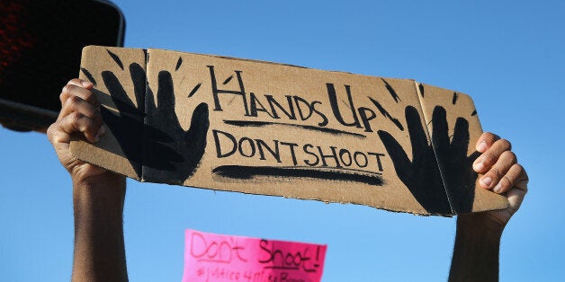 FERGUSON, MO - AUGUST 13: Demonstrators, protesting the shooting death of teenager Michael Brown, hold up signs after they w