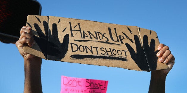 FERGUSON, MO - AUGUST 13: Demonstrators, protesting the shooting death of teenager Michael Brown, hold up signs after they were ordered off the street on August 13, 2014 in Ferguson, Missouri. Brown was shot and killed by a Ferguson police officer on Saturday. Ferguson, a St. Louis suburb, has experienced three days of violent protests since the killing. (Photo by Scott Olson/Getty Images)