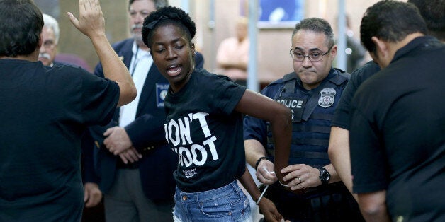 MIAMI, FL - AUGUST 14: Marie Paul is arrested is arrested by police in the James Lawrence King Federal Justice Building where the U.S. Attorneys Office, Southern District of Florida, is located on August 14, 2014 in Miami, Florida. The protesters, which included members of the civil rights group Dream Defenders, say they want justice for Mike Brown, shot and killed by police in Ferguson, Missouri on August 9. They said they also want justice for 17-year old graffiti artist Israel Hernandez, who died from shock from a Miami Beach police officer's Taser last summer. (Photo by Joe Raedle/Getty Images)