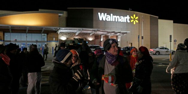 FERGUSON, MO - NOVEMBER 27: people stand outside near National Guard troops and police officers positioned outside of a closed Walmart November 27, 2014 in Ferguson, Missouri. Local businesses still remain closed to consumers in Ferguson as tension continue to still run high the community after Michael Brown, a 18-year-old black male teenager was fatally wounded by Darren Wilson, a white Ferguson Police officer on August 9, 2014. A St. Louis County 12-member grand jury who reviewed evidence related to the shooting decided Monday not to indict Wilson with charges sparking riots through out Ferguson. (Photo by Joshua Lott/Getty Images)