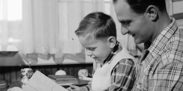 circa 1956: A son reads with his father. (Photo by Three Lions/Getty Images)