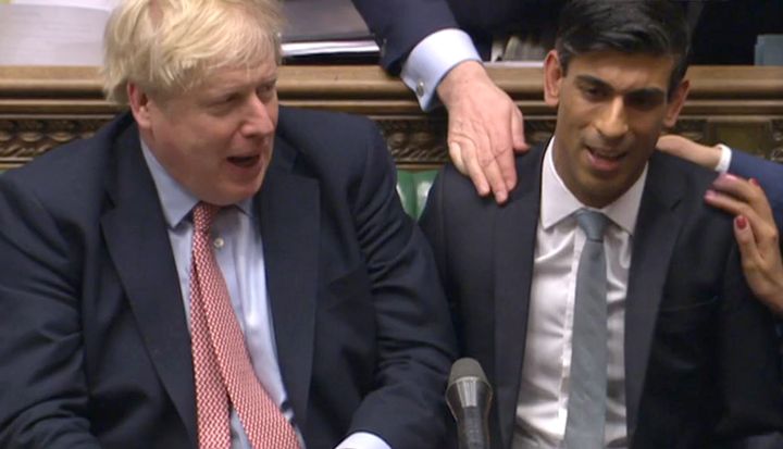 Chancellor Rishi Sunak (right) sits down after delivering his Budget in the House of Commons, London.