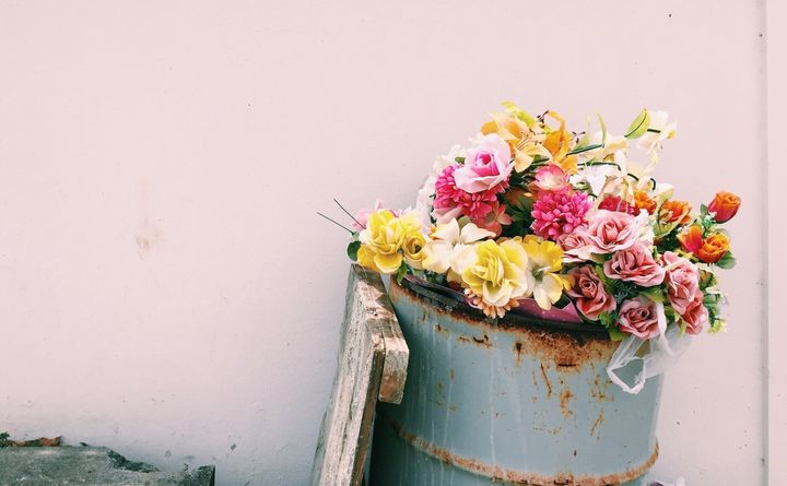 Flower Bouquet In Garbage Can Against Wall