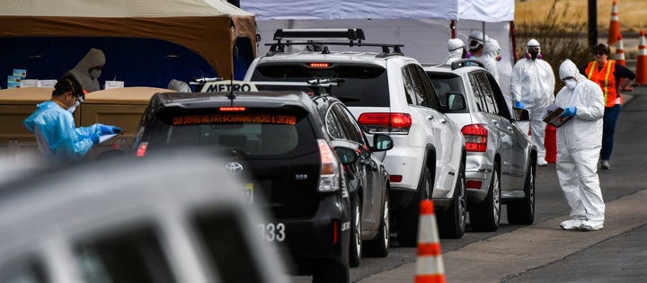 Health care workers test people for COVID-19 at Colorado's first drive-up testing center in Denver.
