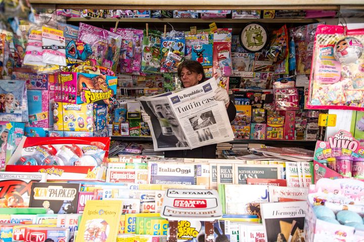 イタリア・サレルノの新聞スタンドで、手袋をして新聞を読む販売員。手にした新聞には、“Tutti a casa（全員自宅待機)” と書かれている / 3月10日