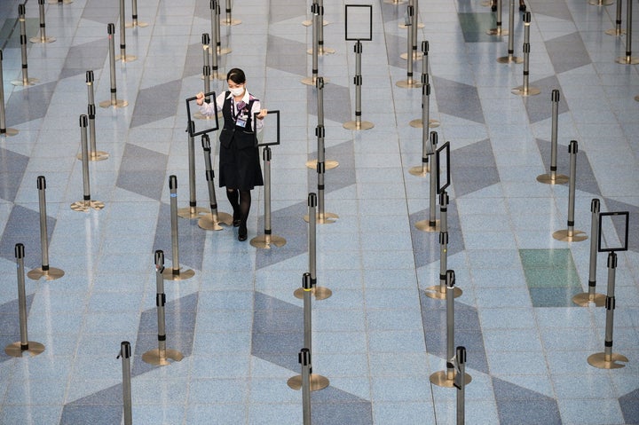 東京・羽田空港の出発ロビーで、マスクをして作業する航空会社の職員 / 3月10日