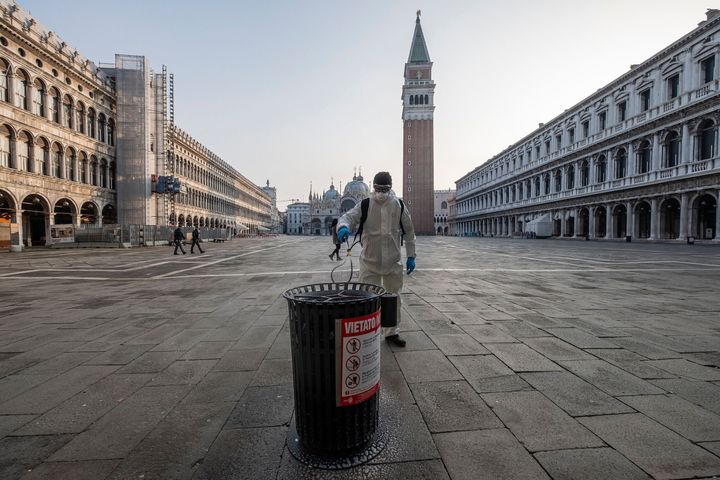 イタリア、ベネチアのサン・マルコ広場では、環境作業員が防御服でゴミ箱を消毒した / 3月11日