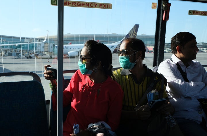 Passengers wearing masks as a precaution against a coronavirus ride a bus at Chhatrapati Shivaji International Airport in Mumbai, March 10, 2020. 