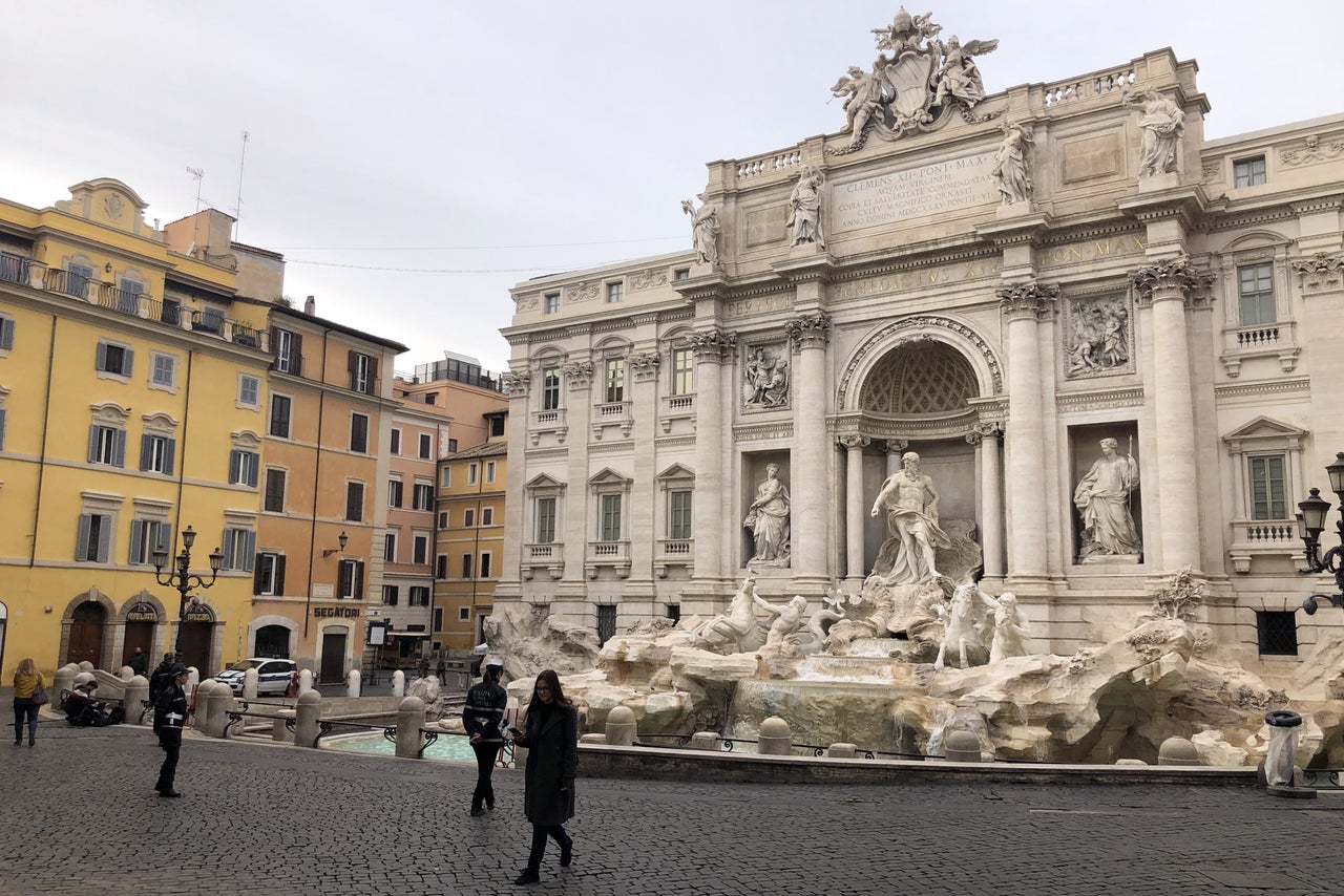 Tourists and police officers by the usually-crowded Trevi Fountain in Rome. 