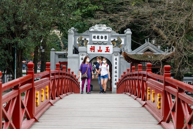 Foreign tourists wear protective masks and walk on the empty The Huc bridge on Hoan Kiem lake in Hanoi, Vietnam.