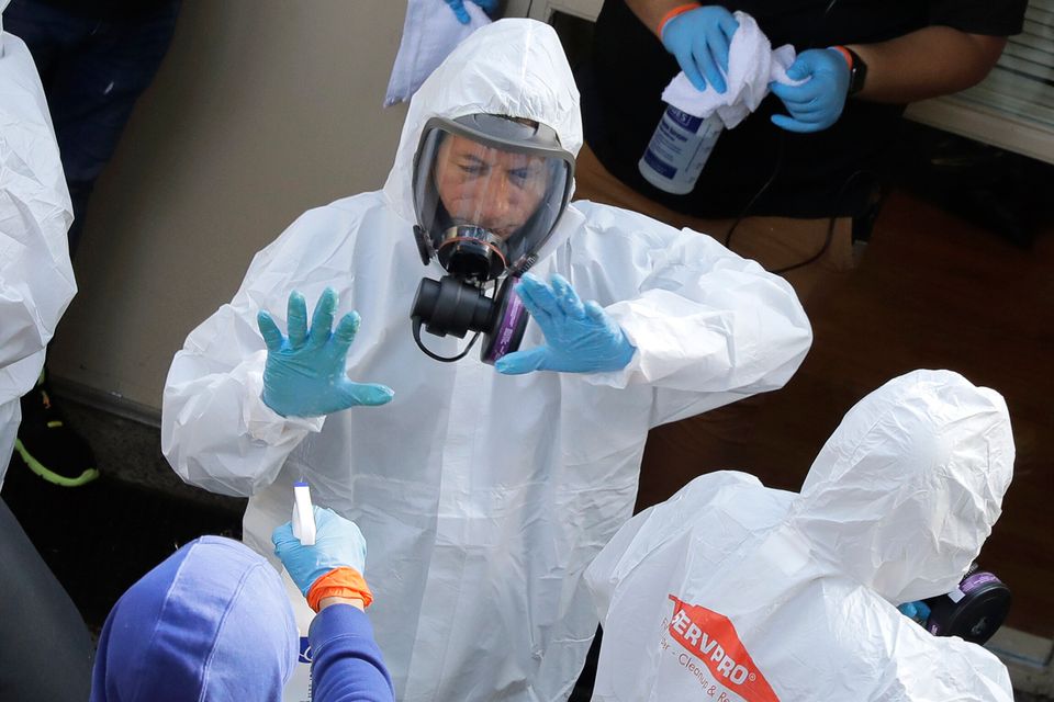 Servpro cleaning workers are sprayed as they exit the Life Care Center in Kirkland, Washington