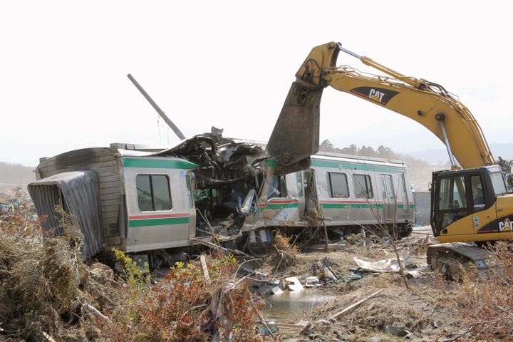 大津波を受けJR常磐線新地駅で脱線、転覆した列車の撤去作業が始まり、業者が重機を使って車体を解体した。スクラップにして運び出す予定という（福島・新地町）