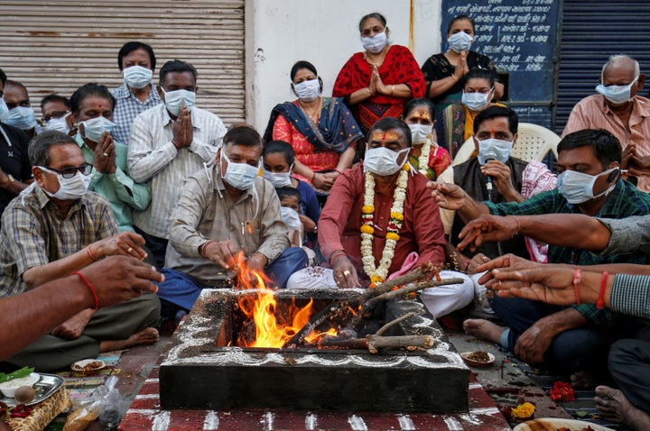 Hindu residents wearing protective masks perform prayers for protection against coronavirus disease (COVID-19), outside a temple, in Ahmedabad, Gujarat.