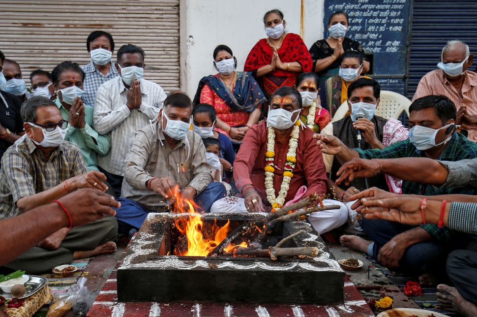 Hindu residents wearing protective masks perform prayers for protection against coronavirus disease (COVID-19), outside a temple, in Ahmedabad, Gujarat.