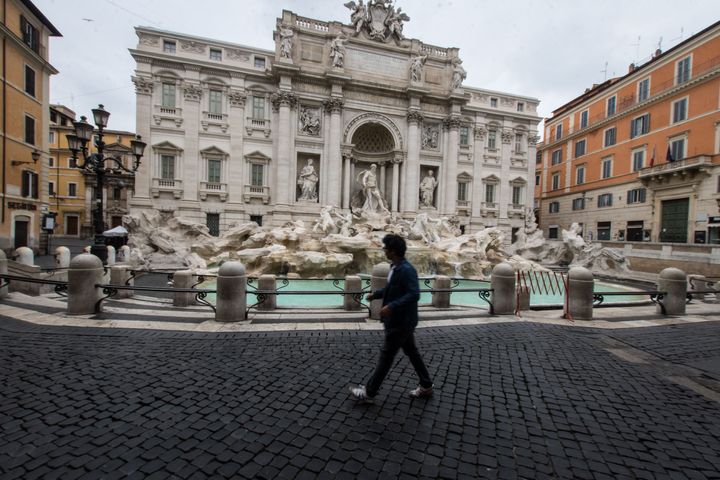 A man walks past the Trevi fountain in Rome, Saturday, March 14, 2020. Italians have been experiencing yet further virus-containment restrictions after Premier Giuseppe Conte ordered restaurants, cafes and retail shops closed after imposing a nationwide lockdown on personal movement. For most people, the new coronavirus causes only mild or moderate symptoms. For some it can cause more severe illness. (Photo by Andrea Ronchini/NurPhoto via Getty Images)