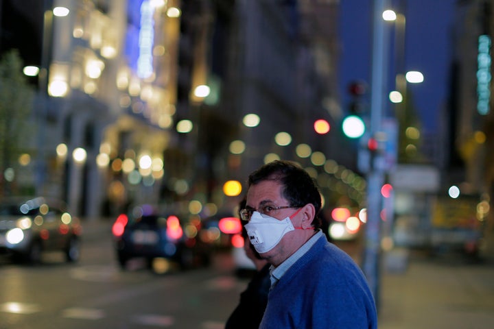 A man wears a face mask at the Gran Via avenue in downtown in Madrid, Spain, Saturday, March 14, 2020.