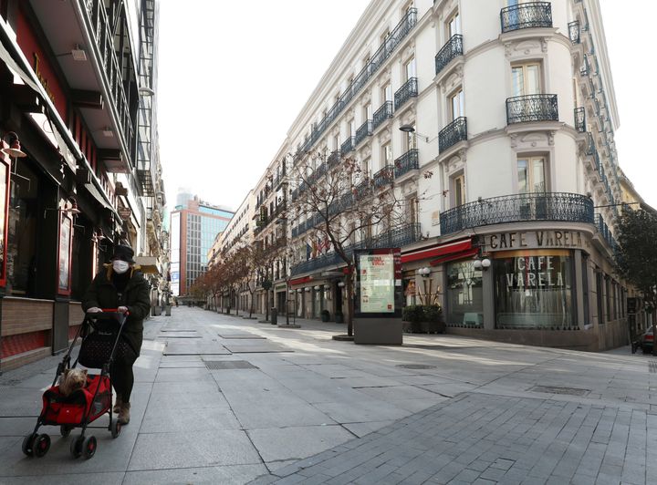 A woman, wearing a protective face mask, walks in an empty central street during partial lockdown in Madrid.