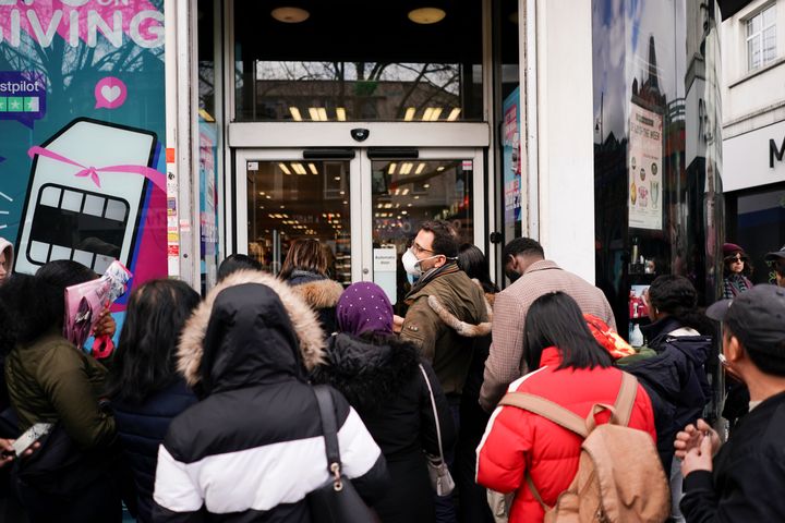 People, some wearing protective face masks, queue outside of a pharmaceutical shop before it opens, as the number of coronavirus cases grow around the world, in London.
