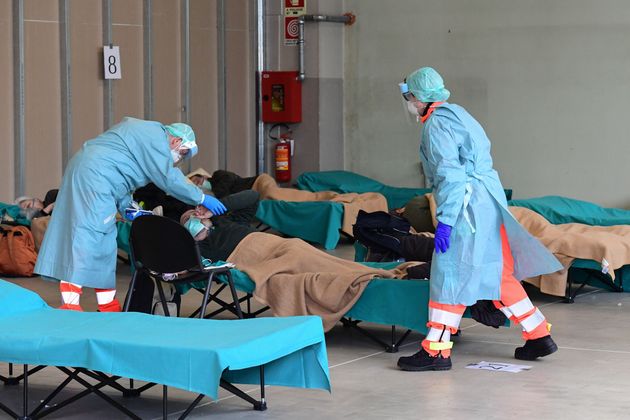 Hospital employees wearing a protection mask and gear tend to a patient at the Brescia hospital, Lombardy, on March 13, 2020. 