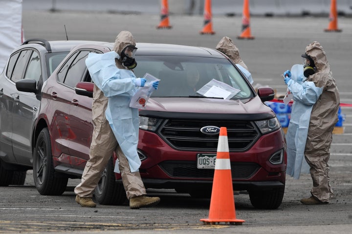 Colorado National Guard members assist the Colorado Department of Public Health and Environment in providing free, drive-up testings for coronavirus in the parking lot of the Denver Coliseum.