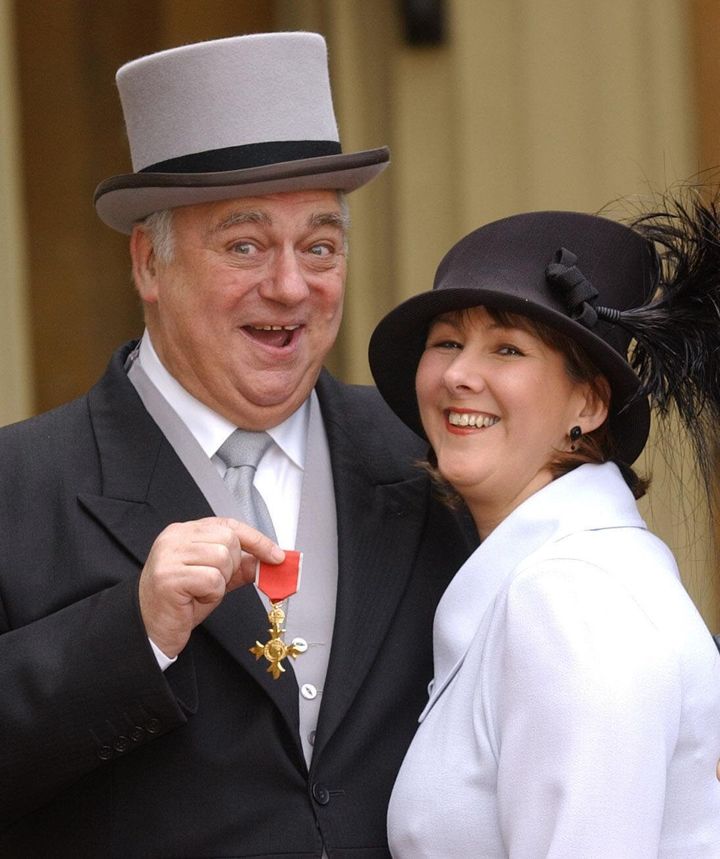 Roy Hudd with his wife Debbie, holding his OBE for services to entertainment, at Buckingham Palace, London in 2004.