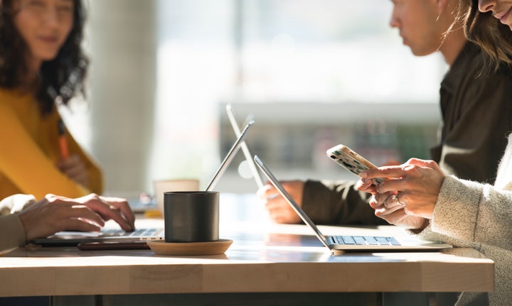 This stock photo shows young people working on laptops at a cafe. Canadian telecoms are making it more affordable for customers to stay in touch.