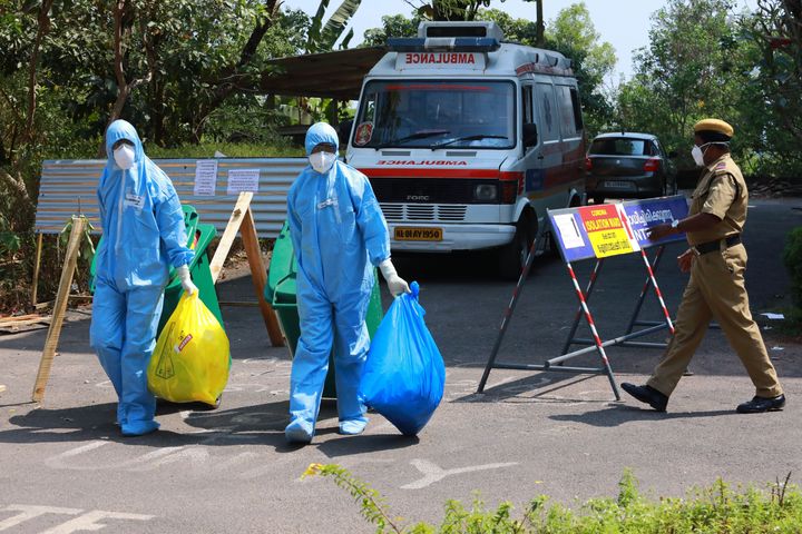 Heath officials in full protective gear carry medical waste out of an isolation ward of Ernakulam medical college, in Kochi on February 4, 2020.