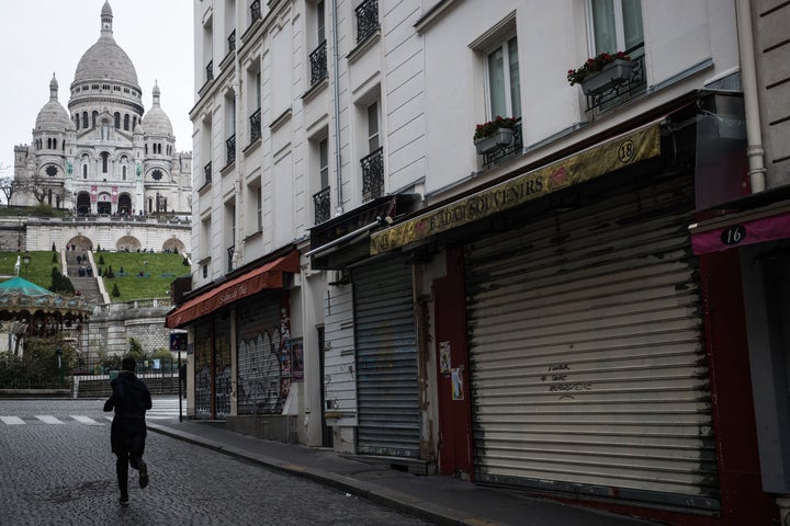 A man runs near the Sacre Coeur Basilica in the Montmartre area in Paris on March 16, 2020, as all non-essential public places including restaurants and cafes have been closed to contain the spread of the COVID-19, caused by the novel coronavirus.